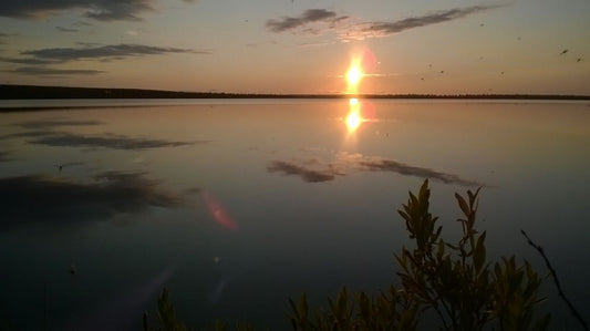 Auringon lasku tyynellä tunturijärvellä.