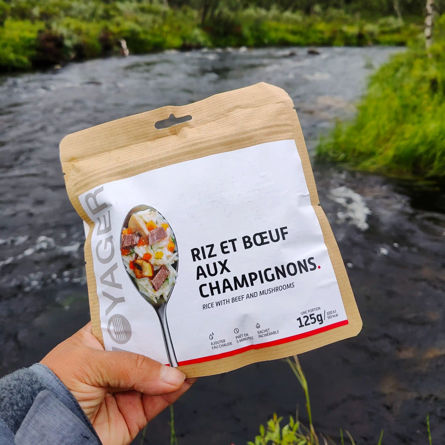 Härkäpataa riisillä ja sienillä retkiruokapussi kädessä joen ääressä.