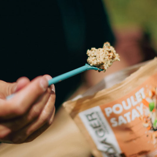 Retkiruoka kana satayta valmiina haarukassa taustalla retkiruokapussi