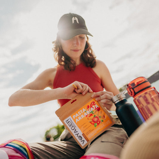 Lippalakkipäinen nainen avaamassa pasta arrabiata retkiruokapussia