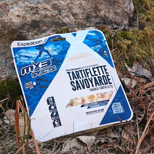 Retkiruoka Alppien perunagratiini maassa keväisessä varvikossa kiven edessä.