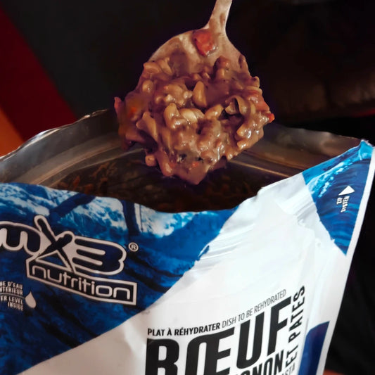 Retkiruoka Burgundin pataa ja pastaa valmiina lusikassa retkiruokapussin päällä.