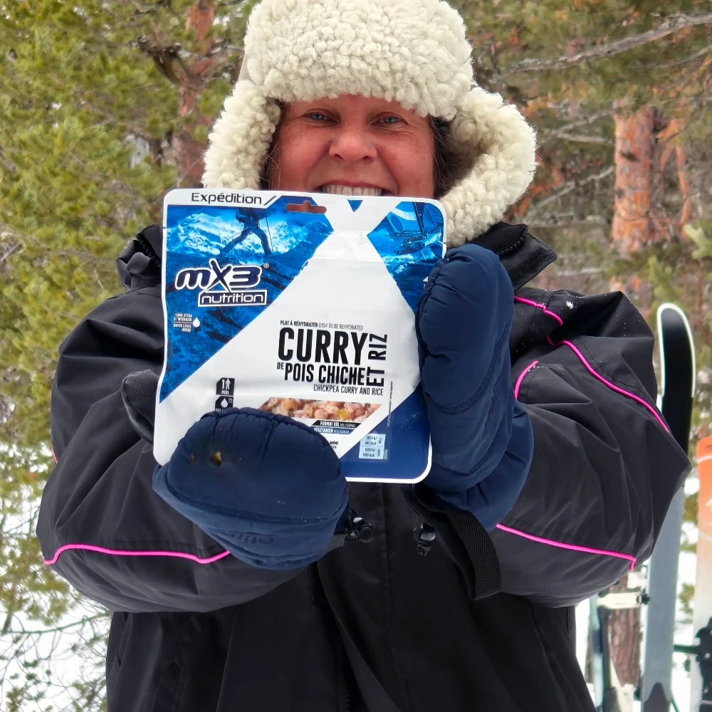 Retkiruokapussi kikhernecurry mustatakkisen karvahattuisen naisen kädessä talvella.