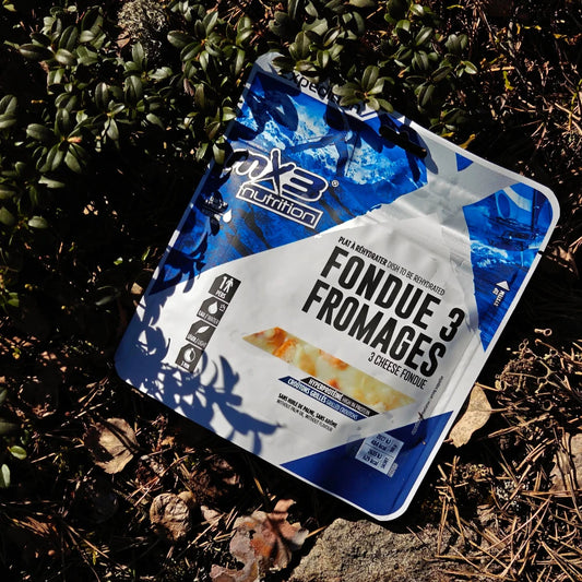 Retkiruoka kolmen juuston fondue maassa keväisessä varvikossa.