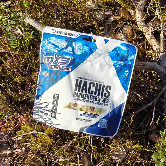 Retkiruoka nyhtöliha-perunasoselaatikko maassa keväisessä varvikossa.