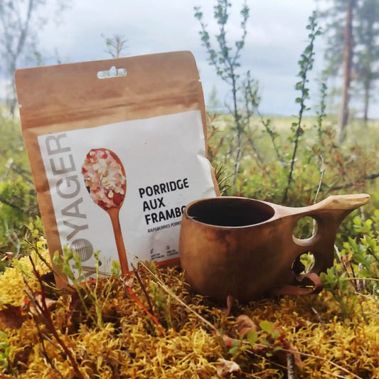 Vadelmaista kaurapuuroa retkiruoka ja kuksa sammaleen päällä maassa.