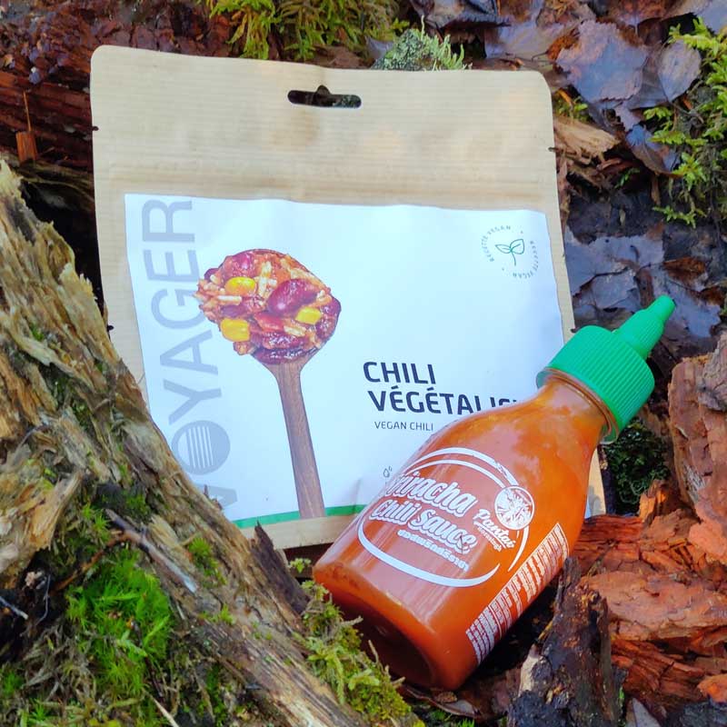 Retkiruoa Chili sin Carne lahonneen kannon vieressä, edesää vihreä korkkinen pullo shiracha-kastiketta.