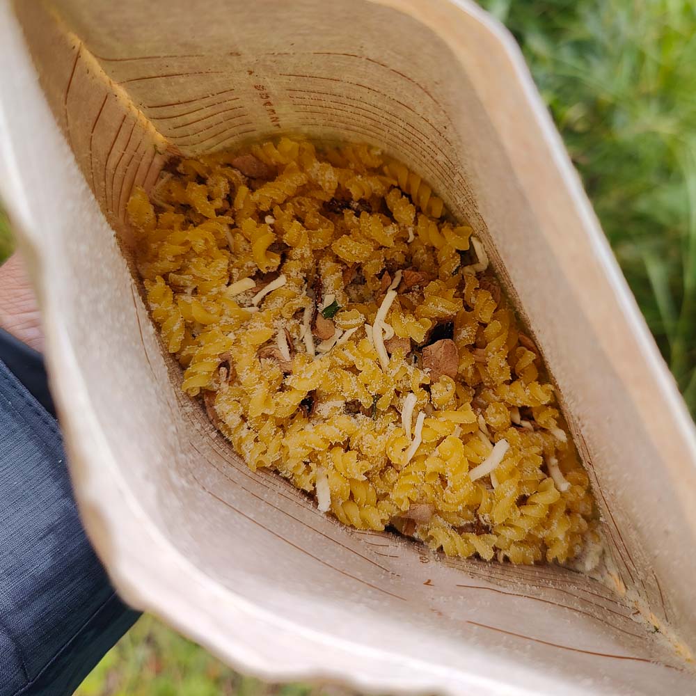 Juustoinen sienipasta-retkiruokapussi avattuna ja kuiva sisältö esillä.