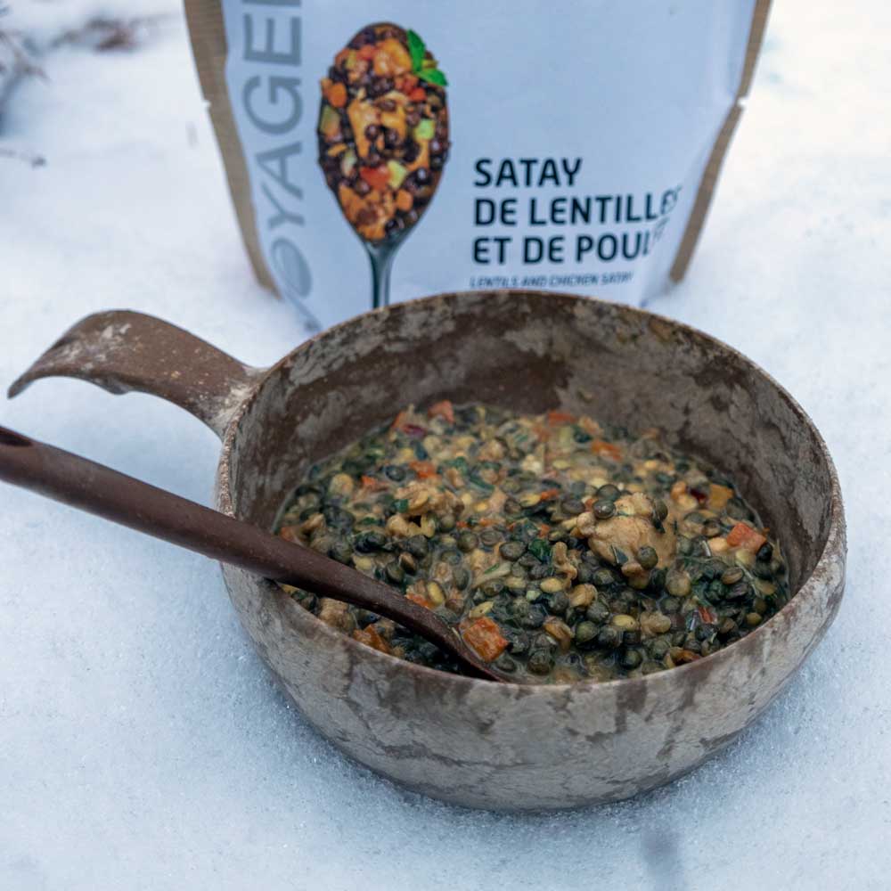 Kana-linssisatay retkiruoka valmiina kupilka-astiassa, takana retkiruokapussi.