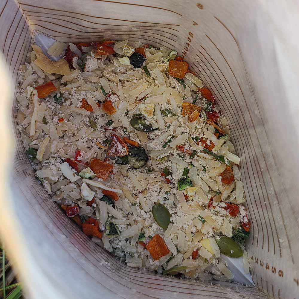 Mausteinen kasvisrisotto kurpitsansiemenillä avatussa retkiruokapussissa kuivana.