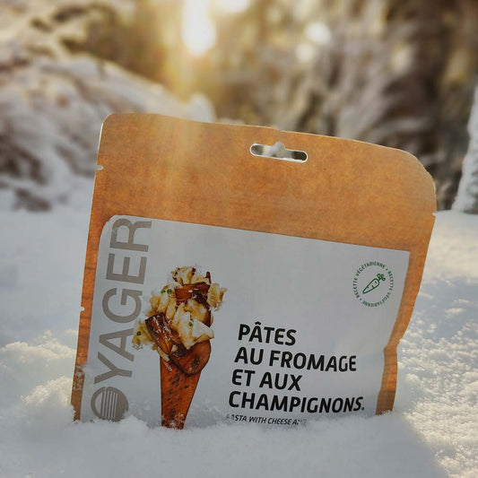 Juustoinen sienipasta retkiruokapussi puhtaassa hangessa auringon paisteessa.